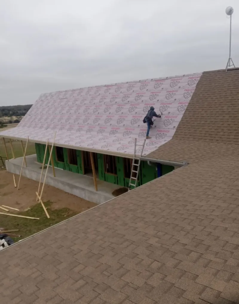 Worker preparing underlayment for a metal roof installation in Waupun
